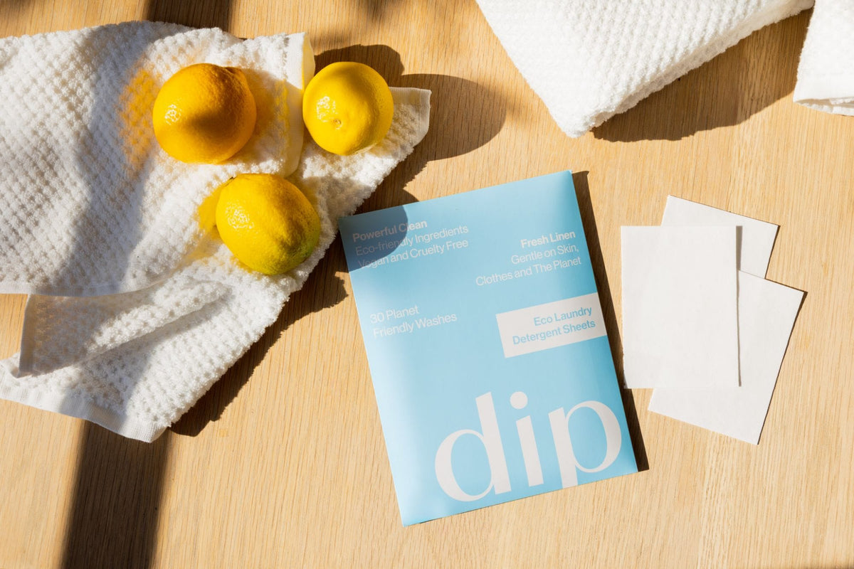 A pack of Dip Fresh Linen laundry sheets with three sheets beside it on a wooden table